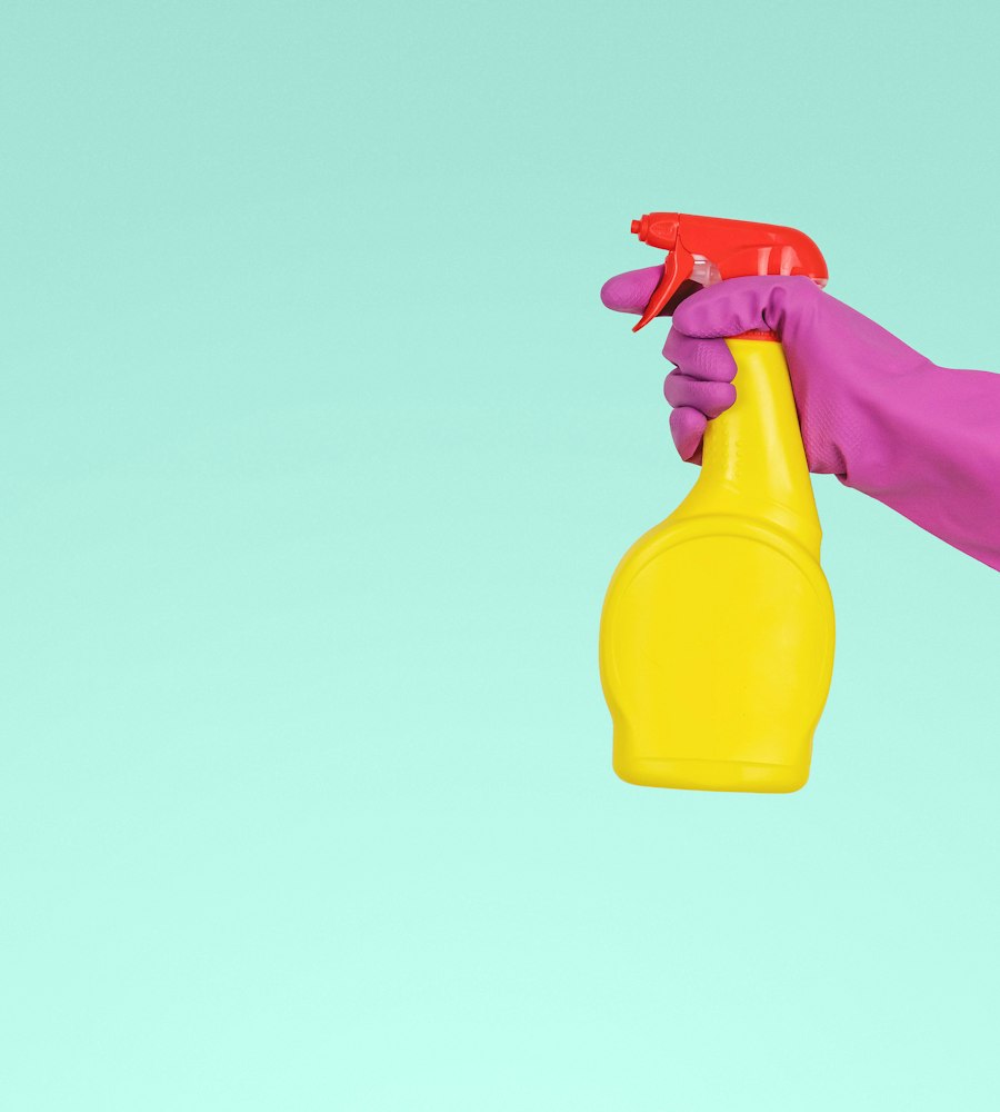 Cleaner holding a yellow spray bottle
